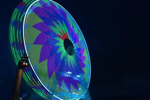 Ferris wheel with bright lights of different colours at the fun fair Stock Photos