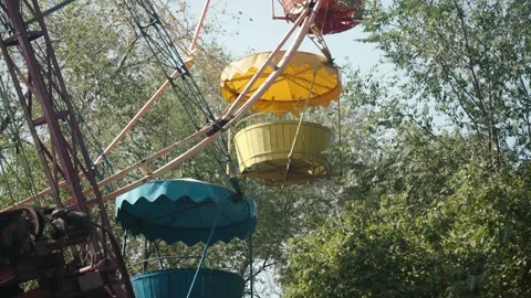 Ferris wheel cabins seen through green leaves in summer amusement park Stockbeeldmateriaal 319535131