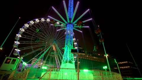 Ferris Wheel with a carousel at night rotating, dynamically illuminated Stock Footage 223786788