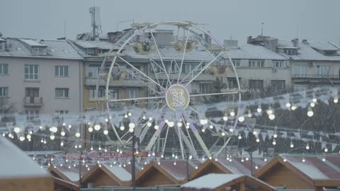 Ferris wheel at a Christmas market in Sofia with snow-covered roofs Stock Footage 296229961