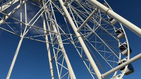Ferris wheel featuring colourful seating pods against backdrop of blue sky Stock Footage 310141046