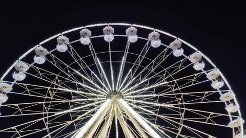 Ferris wheel, illuminated by lights, rotates against background of night sky. Stock Footage 327903170