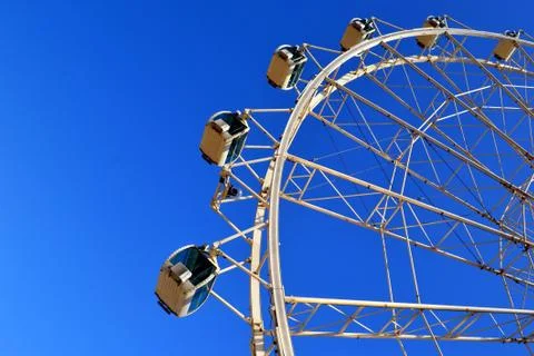 Ferris wheel in motion against the background of a blue cloudless sky Stock Photos