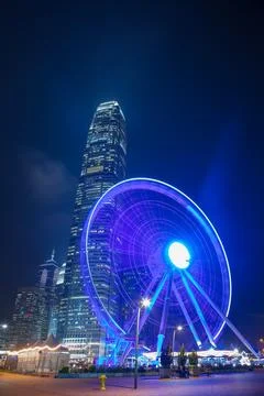 Ferris Wheel at Night with a Skyscraper in the Background in Hong Kong Stock-Fotos