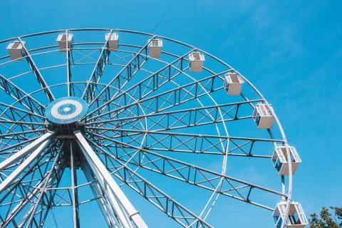 Ferris wheel in a park on a clear blue background. Stock Photos