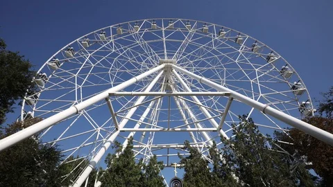 Ferris wheel rotates on blue sky background, wide angle shot, bottom view Video stock 116500622