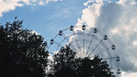 A Ferris wheel is seen turning in the background with trees framing the view. Vídeo Stock 344528031