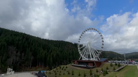 Ferris wheel spinning in front of pine forest and cloudy sky Stock Footage 280008527