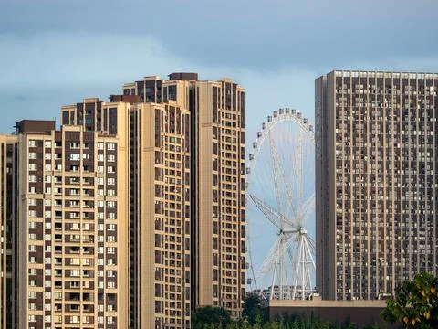 Ferris wheel visible between the gap of two high rise buildings. Stock Photos