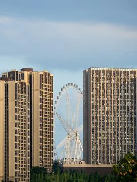 Ferris wheel visible between the gap of two high rise buildings. Stock Photos