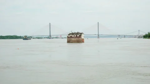 Ferry Boat Navigating Wide River with Bridge in Background Видео 334226942