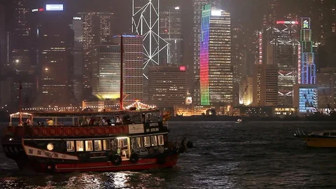 Ferry boats sailing in the river in front of the illuminated Hong Kong skyline Stock Footage 97102374