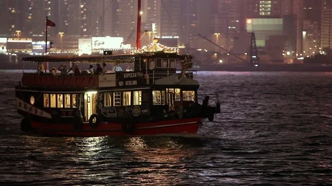 Ferry boats sailing in the river in front of the illuminated Hong Kong skyline Stock Footage 97102420