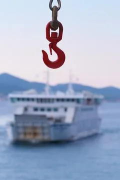Ferry crane hook close-up and a ferry visible in background Stock Photos