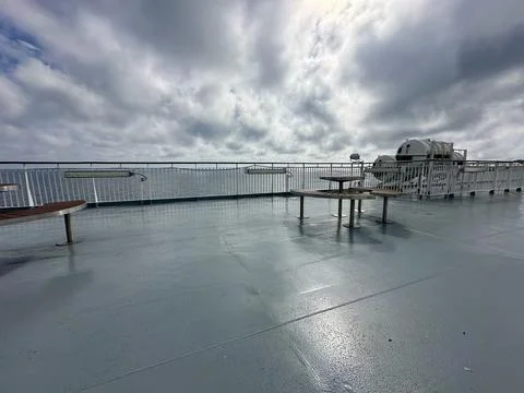 Ferry deck with table and benches, cloudy sea view. Editorial Stock Photos