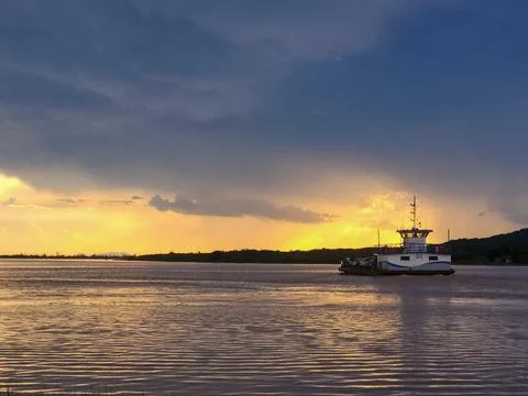 A ferry on a dense river heading towards the mainland Stock Photos
