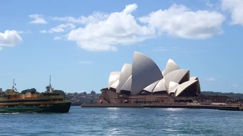 A ferry glides over Sydney Harbour’s sparkling water as the iconic Opera House Vidéo 339844514
