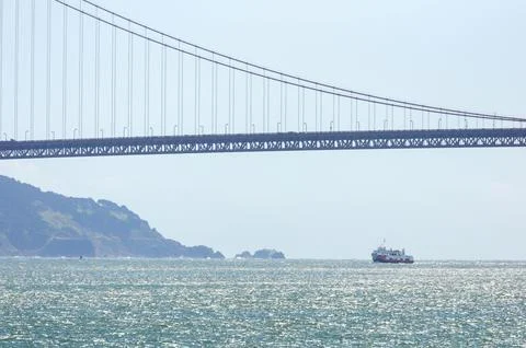 Ferry glides under iconic bridge on sunny day in San Francisco Bay Foto stock