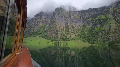  Ferry on Koenigssee glides through emerald alpine waters with dramatic mountain Stock Footage 309028558