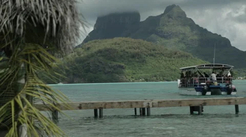 Ferry leaving dock with Bora Bora Island backdrop, framed by Palm Fronds Vidéo 68101413