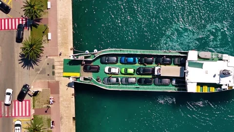 Ferry loading cars at dock with pedestrians walking nearby along waterfront area Stock Footage 338164840