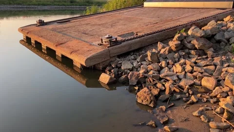 Ferry loading ramp extending over calm river water at golden hour Stock Footage 343701817