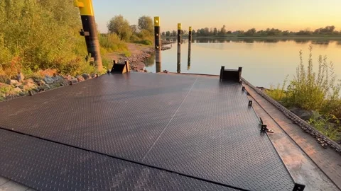 Ferry loading ramp extending toward calm river at golden hour Stock Footage 343701648