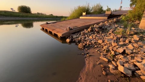 Ferry loading ramp over calm river water at golden hour Stock Footage 343701886