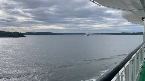 Ferry navigates calm waters, passing another vessel in scenic coastal landscape Vídeos de archivo 343187135