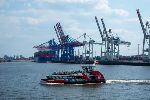 Ferry Navigating Busy Harbor with Cargo Ships and Cranes Stock Photos