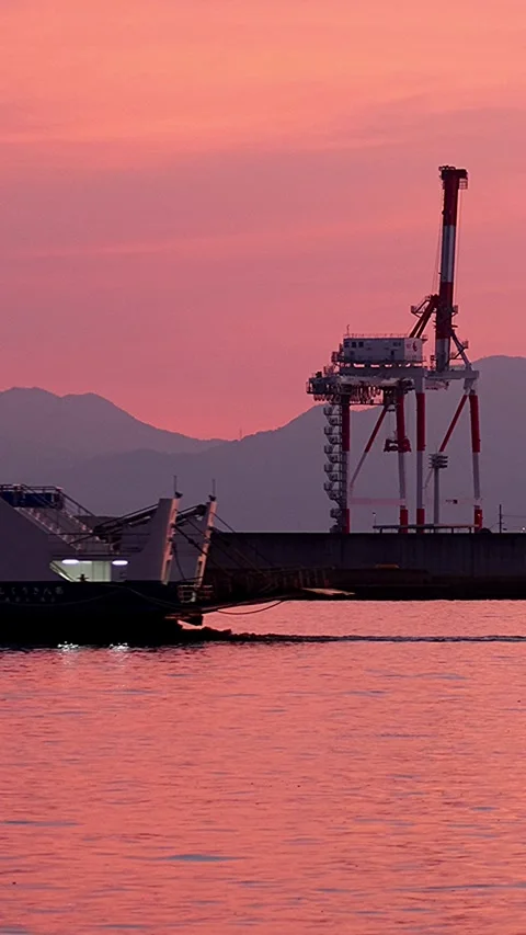Ferry Passing in Front of Gantry Cranes in a Pink Sunset Japanese Harbor,Vertic Video stock 341113289