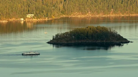 Ferry passing in front of small island near Vancouver Island at sundawn Stock Footage 128096996