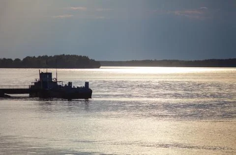 Ferry pier on the river in beams setting the sun Stock Photos