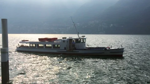 Ferry sails slowly from the dock of cernobbio near the pylons Stock Footage 118649725
