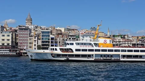 A ferry sails through the Bosphorus Strait against the backdrop of the Galata Vídeo Stock 345603563