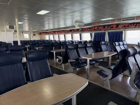 Ferry seating area with empty blue chairs and tables in a spacious interior.. Stockfoto's