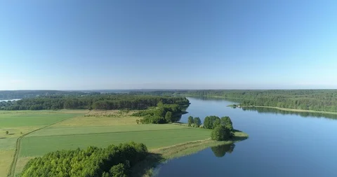 Fertile green fields lush forest and a clear surfaced lake in rural setting Vídeo Stock 90953335