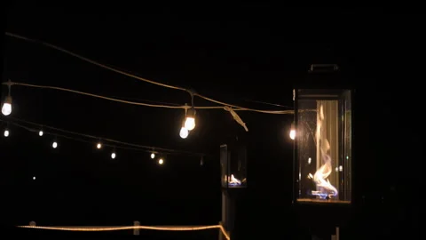 The festival decorative string lights and fire lamp, street lights glow outdoors Stock Footage 304303520