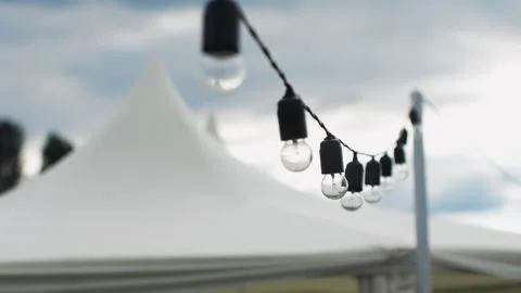 Festival decorative string lights hang and glow outdoors Video stock 164787424
