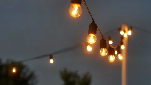 Festival decorative string lights hang and glow outdoors at night Stock-Footage 164788568