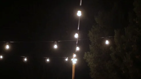 Festival decorative string lights hanging and glowing in the open air at night Stock Footage 127934496