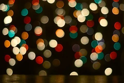 Festive background. A dark table and blurry multicolored lights in the backgr Stock Photos