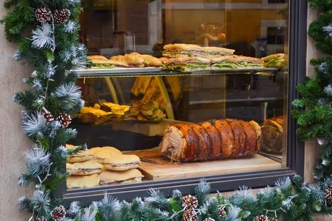 Festive Bakery Window Display with Holiday Decorations and Porchetta Stock Photos
