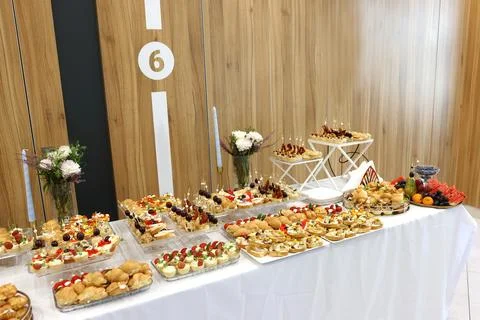A festive buffet table displays assorted canapes, fruits, pastries and floral 스톡 사진