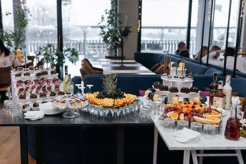 Festive buffet table in a restaurant with desserts, fruits, beverages and tab Stock Photos