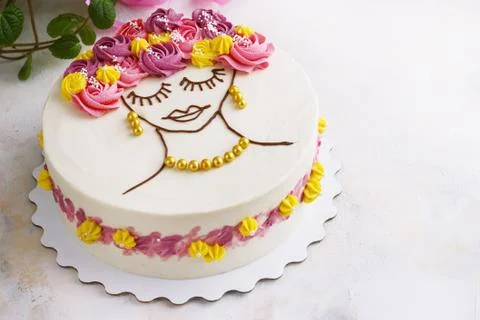 Festive cake with cream flowers and a girl face on a light background Stock Photos