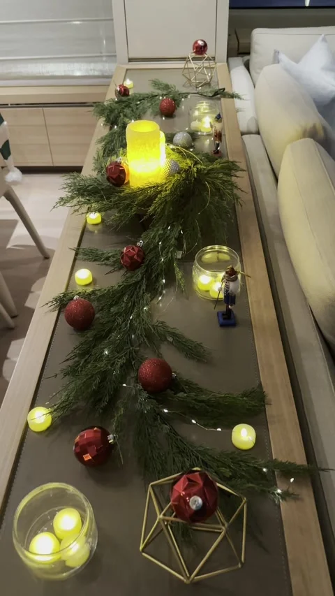 Festive candlelit table decor with pine garland, ornaments, and glowing tea Stock Footage 320499837