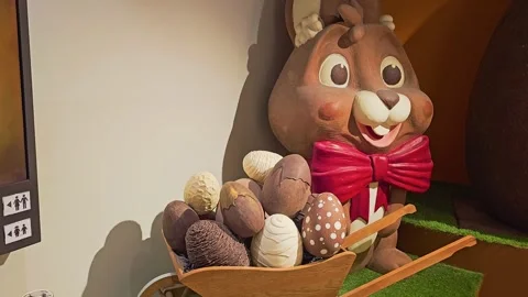Festive chocolate shop Easter display with cartoon bunny, oversized eggs in a 스톡 동영상 335220637