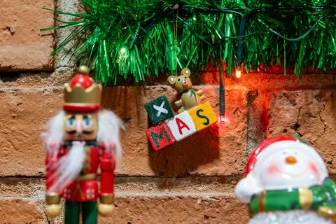 Festive Christmas decor: nutcracker, snowman, 'XMAS' sign, brick wall backg.. Stockfoto's