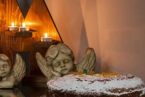 Festive Christmas setup consisting of lit candles, angel statues and a cake. Stock Photos